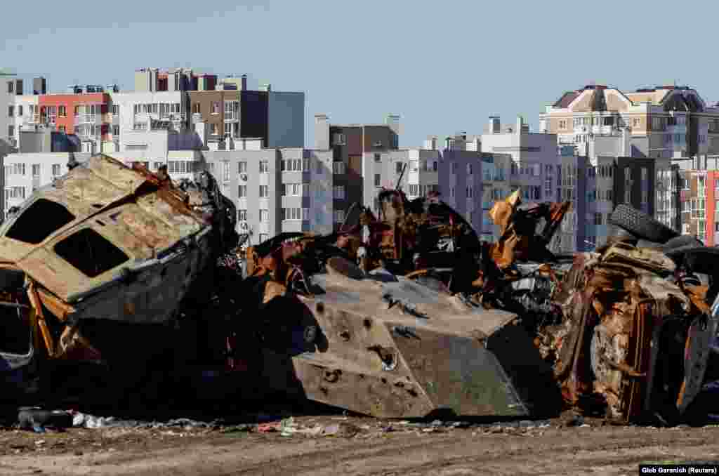 Civilian cars and military vehicle destroyed during the invasion can still be seen near repaired apartment buildings in Bucha before the first anniversary of its liberation.