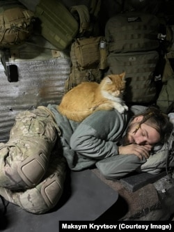 Maksym Kryvtsov with the red-haired cat that was a constant companion in his final months on the front line