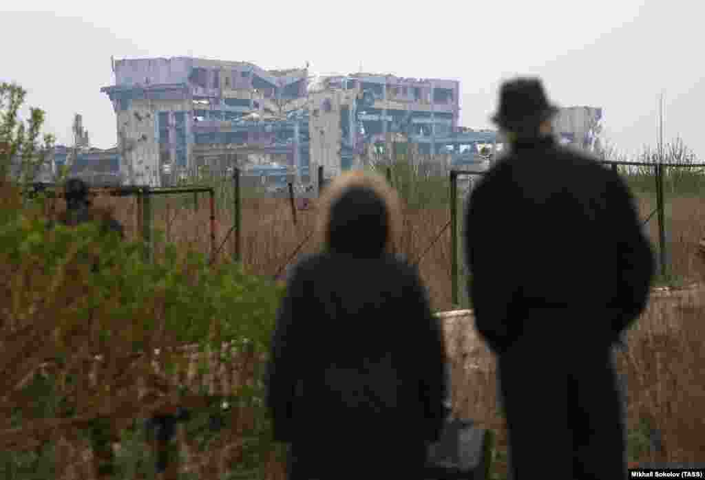 A couple looks at the ruins of the airport in April 2017. After the Kremlin launched its all-out invasion of Ukraine in February 2022, the entire territory of the ruined airport was taken over by Russian forces by November that year.&nbsp;