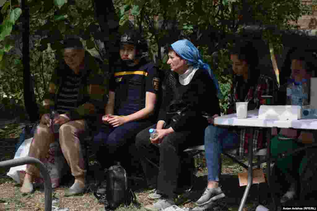 Жінка у синій хустинці – Тетяна. Під завалами рятувальники шукають її маму. Сестра (ліворуч на фото) змогла вибратись зі зруйнованої квартири сама 