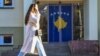 Një vajzë duke kaluar pranë një vitrine ku është varur flamuri i Kosovës.