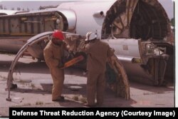 A strategic bomber being broken up by workers with a buzz saw.