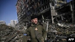 Mikola Madenszki, az ukrán hadserege lelkésze egy lebombázott bevásárlóközpont romjai között Kijevben 2022. március 21-én
