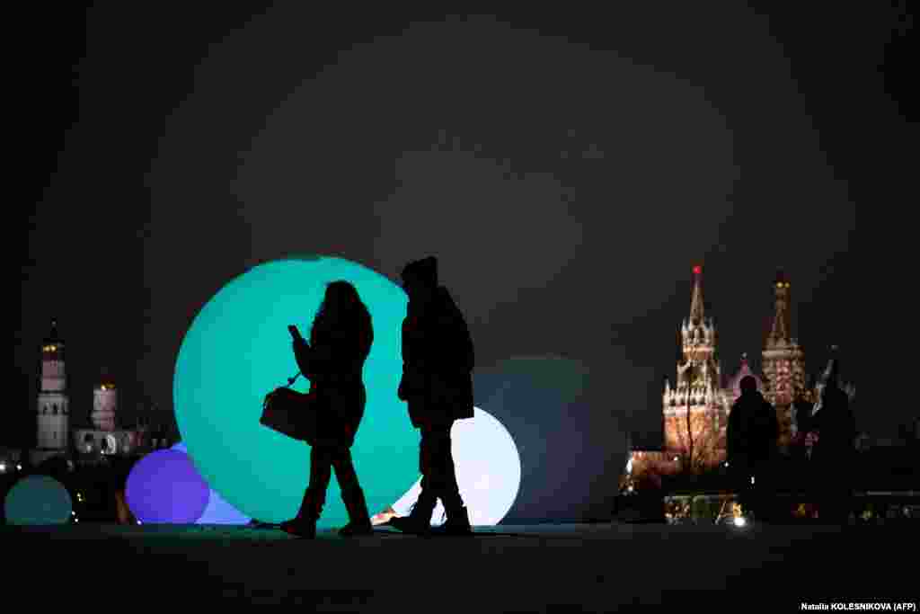 Москвичи проходят мимо праздничных украшений в центральном парке "Зарядье" недалеко от Кремля.