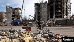 Un bărbat trece cu bicicleta prin orașul Borodyanka recucerit de forțele ucrainene, în timp ce salvatorii caută prin ruine victime ale bombardamentelor rusești, 7 martie 2022 
