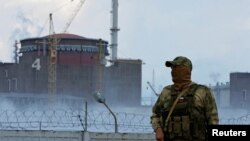 A serviceman with a Russian flag on his uniform stands guard near the Zaporizhzhia nuclear power plant in Ukraine on August 4, 2022.