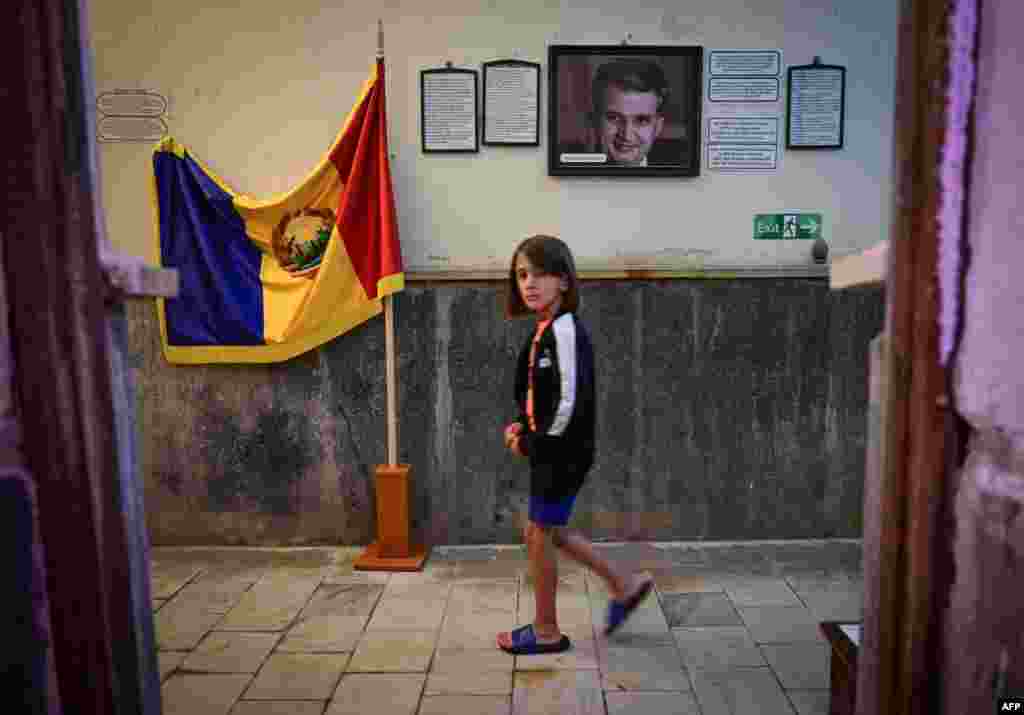A Romanian child walks past a portrait of late communist dictator Nicolae Ceausescu and a flag of socialist Romania displayed for visitors at a private museum in the town of Baile Herculane.