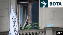 Një zyrtar pranë flamurit të Emiratit Islamik të Afganistanit në ballkonin e Ambasadës afgane në Moskë, 4 korrik.