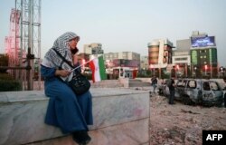An Iranian woman sits close to a destroyed vehicle in Tehran on June 23.