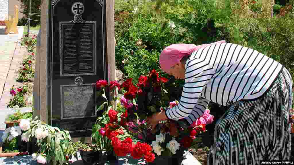 Женщина возлагает цветы у Поклонного креста на территории храма в поселке имени Панфилово.