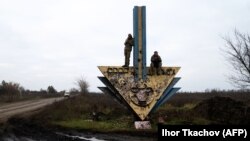 Українські військові намагаються вловити кращий мобільний сигнал на придорожньому знаку на адмінмежі між Харківською та Донецькою областями, 10 листопада 2022 року, ілюстративне фото