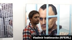 Антон Наумлюк на фоне фотографии Николая Карпюка