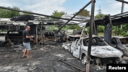 A resident stands next to burned cars at the site of a Russian drone strike in Dnipro, Ukraine, July 26, 2025.