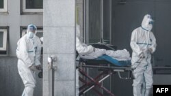 Медики у спеціальних костюмах транспортують інфікованого коронавірусом до лікарні, місто Ухань, 18 січня 2020 року