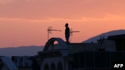 Мужчина стоит на крыше здания, глядя на горизонт в Тегеране 16 июня. Иранская государственная телерадиокомпания была на короткое время отключена от эфира из-за израильского удара, а по всему Тегерану раздались взрывы.