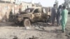 FILE: Residents look at an Army vehicle which was damaged during battle between Afghan security forces and Taliban in Farah Province in May.