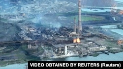Зруйнований російськими обстрілами та бомбардуваннями завод «Азовсталь» на березі Азовського моря. На фото, опублікованому 15 травня 2022 року видно, як на завод сиплються снаряди. Маріуполь. 2022 рік 