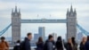 Járókelők London pénzügyi negyedében, háttérben a Tower 2023. október 25-én