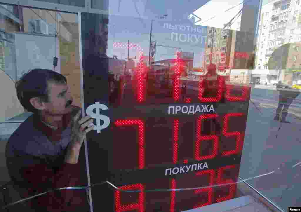Москва, 2015 год. Сотрудник пункта обмена валюты устанавливает курс рубля на табло 