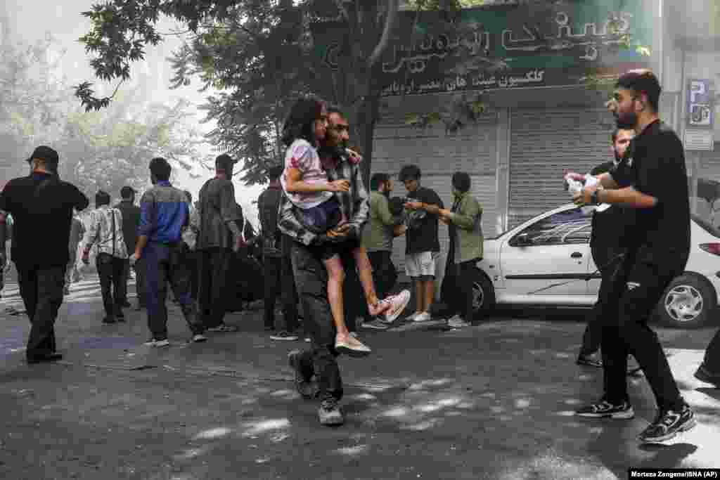A man carries a wounded girl after an explosion in downtown Tehran on June 15 amid Israeli strikes on targets throughout Iran.