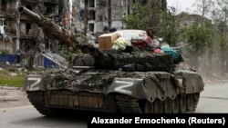 Військовослужбовці РФ проїжджають на танку вулицею повз зруйнований житловий будинок у місті Попасна Луганської області, 26 травня 2022 року, ілюстративне фото