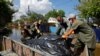 Волонтери і муніципальні працівники складають мішки з тілами загиблих внаслідок повені в окупованій Голій Пристані на Херсонщині, 16 червня 2023 року