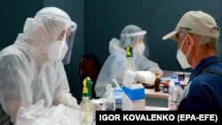Medical workers in protective suits admit patients at a new day hospital Bishkek in July.