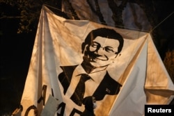 A person walks past a banner with an image of Istanbul Mayor Ekrem Imamoglu during a protest against his detention in Istanbul on March 20.