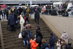 Oameni din Kiev așteaptă la o stație de autobuz pentru a merge în partea de vest a țării.