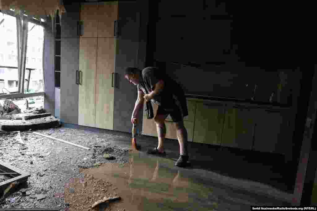 A man cleans up inside the damaged building in the Shevchenkivskiy district.