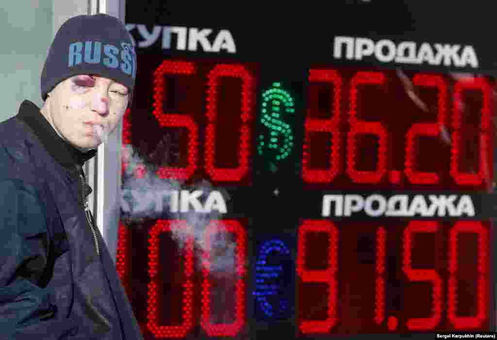 Москва, 2016 год. Мужчина с сигаретой рядом с табло пункта обмена валюты 