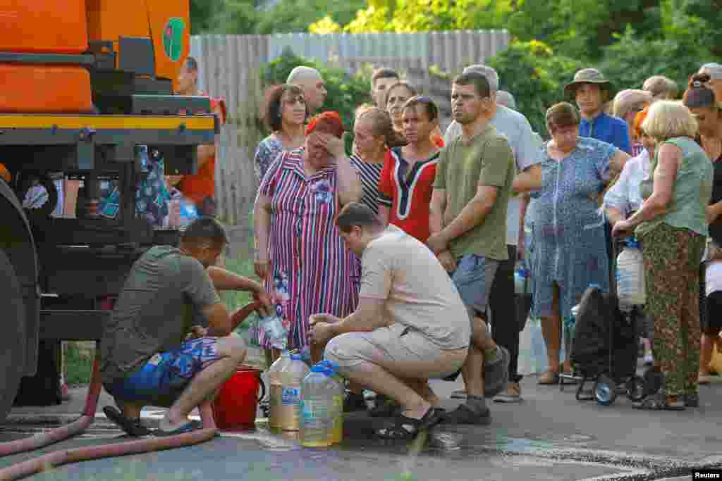 Ukrainians wait in line to collect water delivered by a tank truck in Russian-occupied Donetsk.