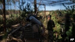 Український солдат несе снаряд у бік гаубиці на передовій в околицях Лиману, Україна, 15 серпня 2023 року