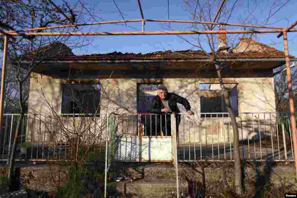 Knezevic pozează în fața casei distruse.