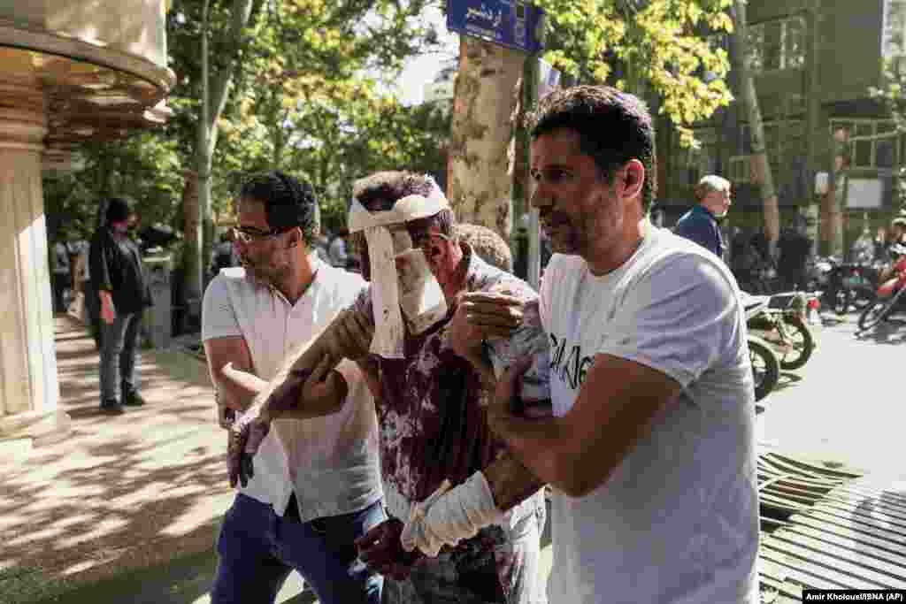 An injured man is led away from the scene of an explosion in central Tehran on June 15.