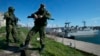 Soldați ruși („omuleții verzi”) păzesc un debarcader cu două nave militare ucrainene în fundal, la Sevastopol, în Peninsula Crimeea, pe 5 martie 2014.